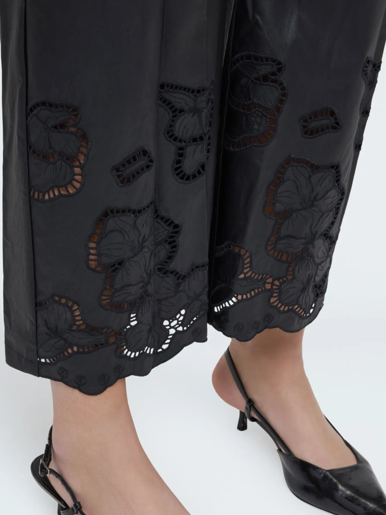 Pantaloni cropped in tessuto spalmato con motivi floreali